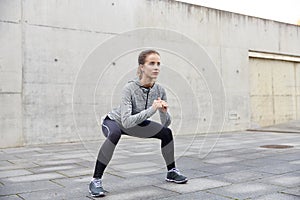 Happy woman doing squats and exercising outdoors