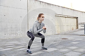 Happy woman doing squats and exercising outdoors