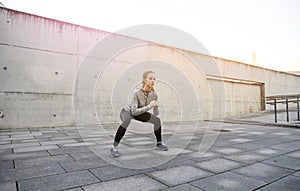 Happy woman doing squats and exercising outdoors