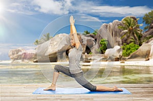 Happy woman doing yoga in low lunge on beach