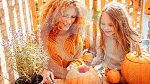 Happy woman drawing on pumpkin with her little daughter