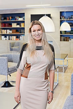Happy woman in dress poses in lounge of business photo