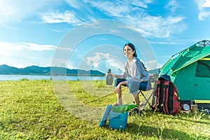 Happy woman drinking alcohol while camping at meadow. People and Lifestyles concept. Travel and adventure theme. Female tourist