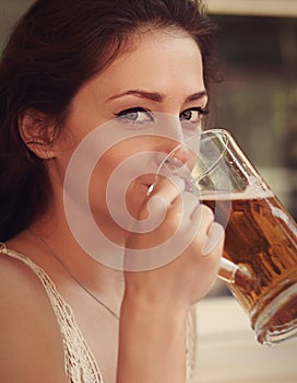 Happy woman drinking beer from big glass