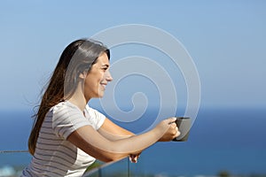 Happy woman drinking coffee in a hotel balcony on the beach