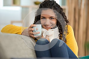 Happy woman drinking coffee on sofa at home