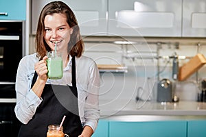 Happy woman drinking a homemade green detox juice, wearing casual clothing