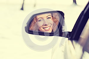 Happy woman driver reflection in car side view mirror. Safe winter trip, journey driving concept