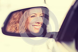 Happy woman driver reflection in car side view mirror