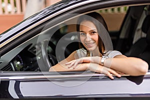 Happy woman driving a car and smiling. Cute young success happy brunette woman is driving a car