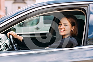 Happy woman driving a car and smiling. Cute young success happy brunette woman is driving a car. Portrait of happy female driver