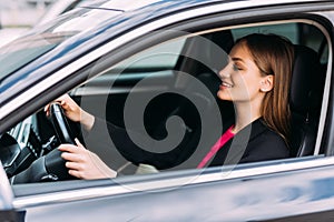 Happy woman driving a car and smiling. Cute young success happy brunette woman is driving a car. Portrait of happy female driver