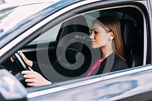 Happy woman driving a car and smiling. Cute young success happy brunette woman is driving a car. Portrait of happy female driver