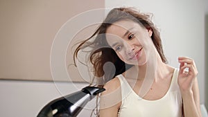 Happy woman drying hair in bathroom. Portrait of young woman dry hair at morning