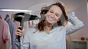 Happy woman drying hair at home. Portrait of brunette woman blowing hair
