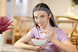 Happy woman eating cereals looking at you