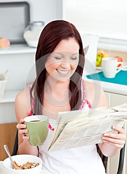 Happy woman eating cereals while reading newspaper