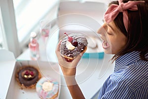 Happy woman eating delicious donuts