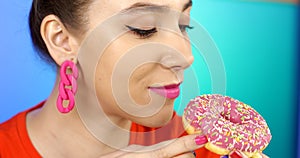 Happy woman eating delicious pink donut.