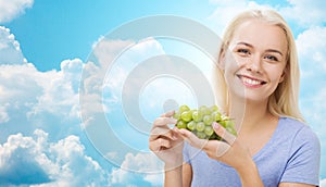 Happy woman eating grapes over sky