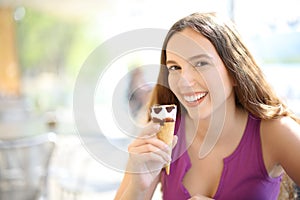 Happy woman eating icecream looking at you in a bar