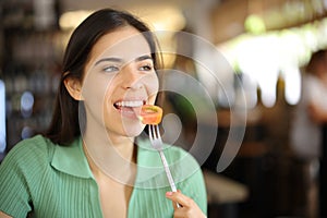 Happy woman eating tomato in a restaurant
