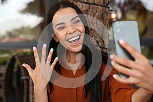 Happy woman with engagement ring taking selfie in outdoor cafe