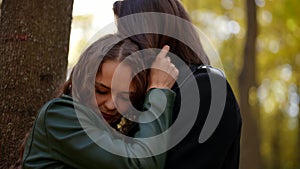 happy woman is enjoying embrace of her husband in park in sunny fall day, pretty lady is snuggling