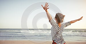 Happy woman enjoying freedom with open hands on sea