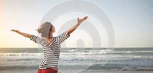 Happy woman enjoying freedom with open hands on sea photo