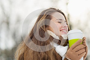 Happy woman enjoying hot beverage in winter park