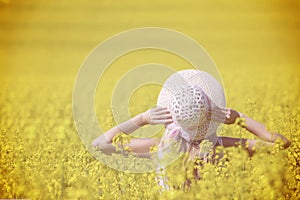 Happy woman enjoying the life in the field with flowers. Nature beauty and colorful field with rape. Outdoor lifestyle. Freedom co