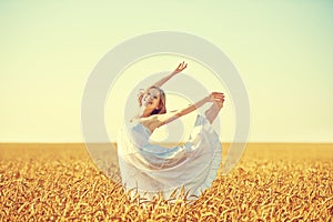 Happy woman enjoying life in golden wheat field