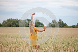 Happy woman enjoying the life in the golden wheat field. She dancing on a field