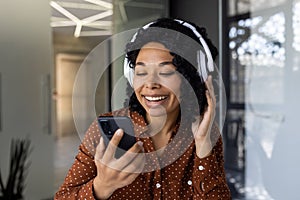 Happy woman enjoying music on headphones while using smartphone