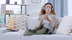 Happy woman enjoying music by her favorite singer on a phone, using headphones. African American female listening to