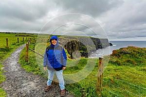 Happy woman enjoying a rainy day on the coastal walk route from Doolin to the Cliffs of Moher