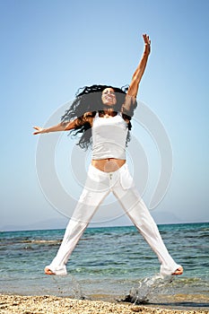 Happy woman exercising on the beach.