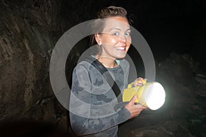 Happy woman explorer holds a flashlight while caving and spelunking underground at Lava Beds National Monument in California