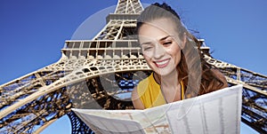 Happy woman exploring attractions in front of Eiffel tower