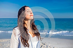 Happy woman with eyes closed at the beach