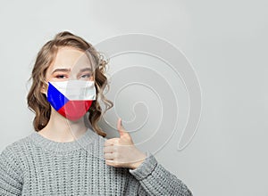 Happy woman in face mask holding thumb up with national flag Czech Republic background. Flu epidemic and protection concept