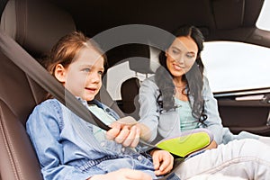 Happy woman fastening child with seat belt in car