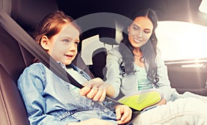 Happy woman fastening child with seat belt in car