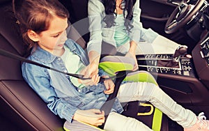 Happy woman fastening child with seat belt in car