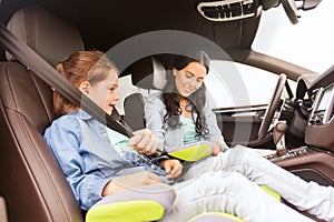 Happy woman fastening child with seat belt in car