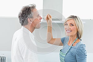 Happy woman feeding man in the kitchen