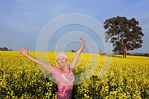 Happy woman in field of golden canola
