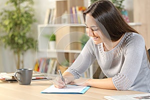 Happy woman filling out form on a desk at home