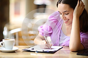 Happy woman filling survey in a coffee shop